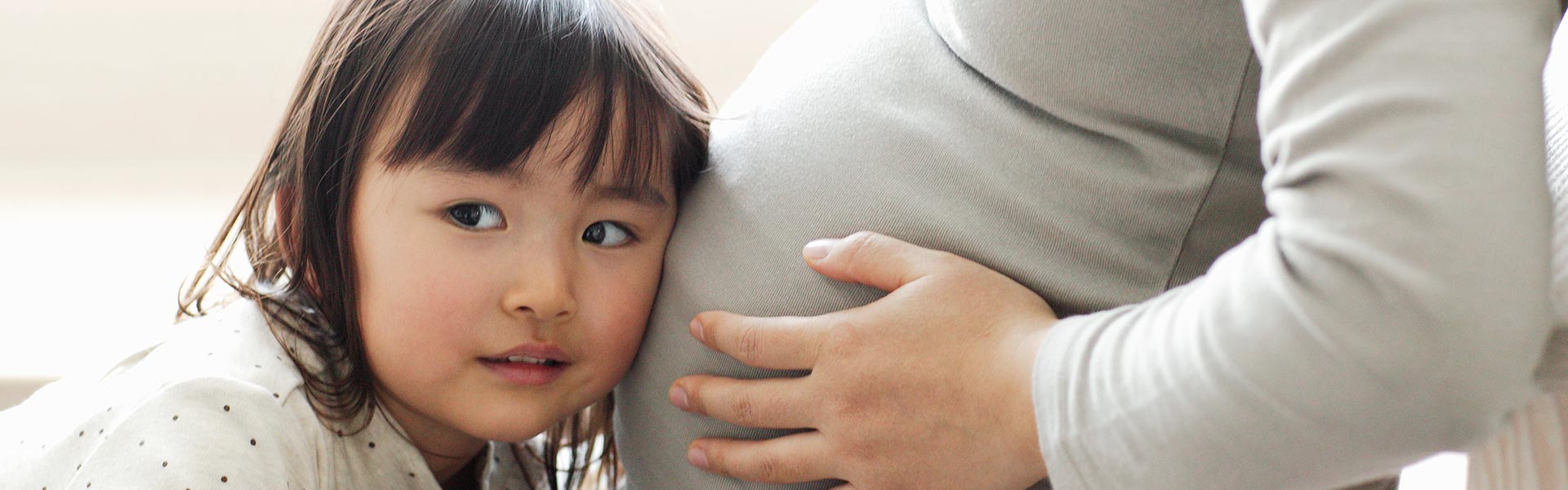 Daughter listening to pregnant mothers stomach