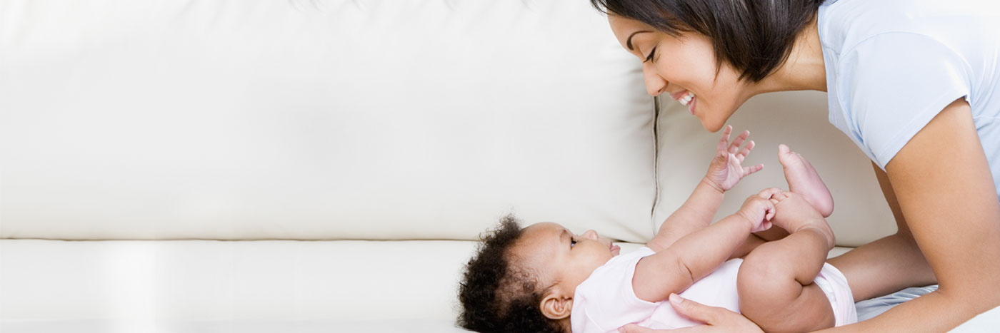 Mother smiling and leaning over child laying on the floor
